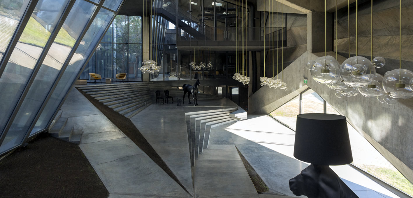 Ein sehr moderner hoher Raum mit vielen Stiegen, viel beton und tief hängenden Lichtern sowie moderner Kunst.