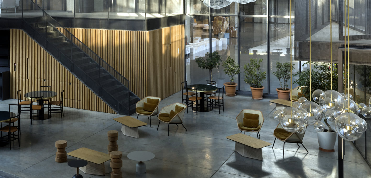ein sehr modernes Büro mit unterschiedlichen Sitzmöglichkeiten, viel Glas, hohe Räume, viele Pflanzen