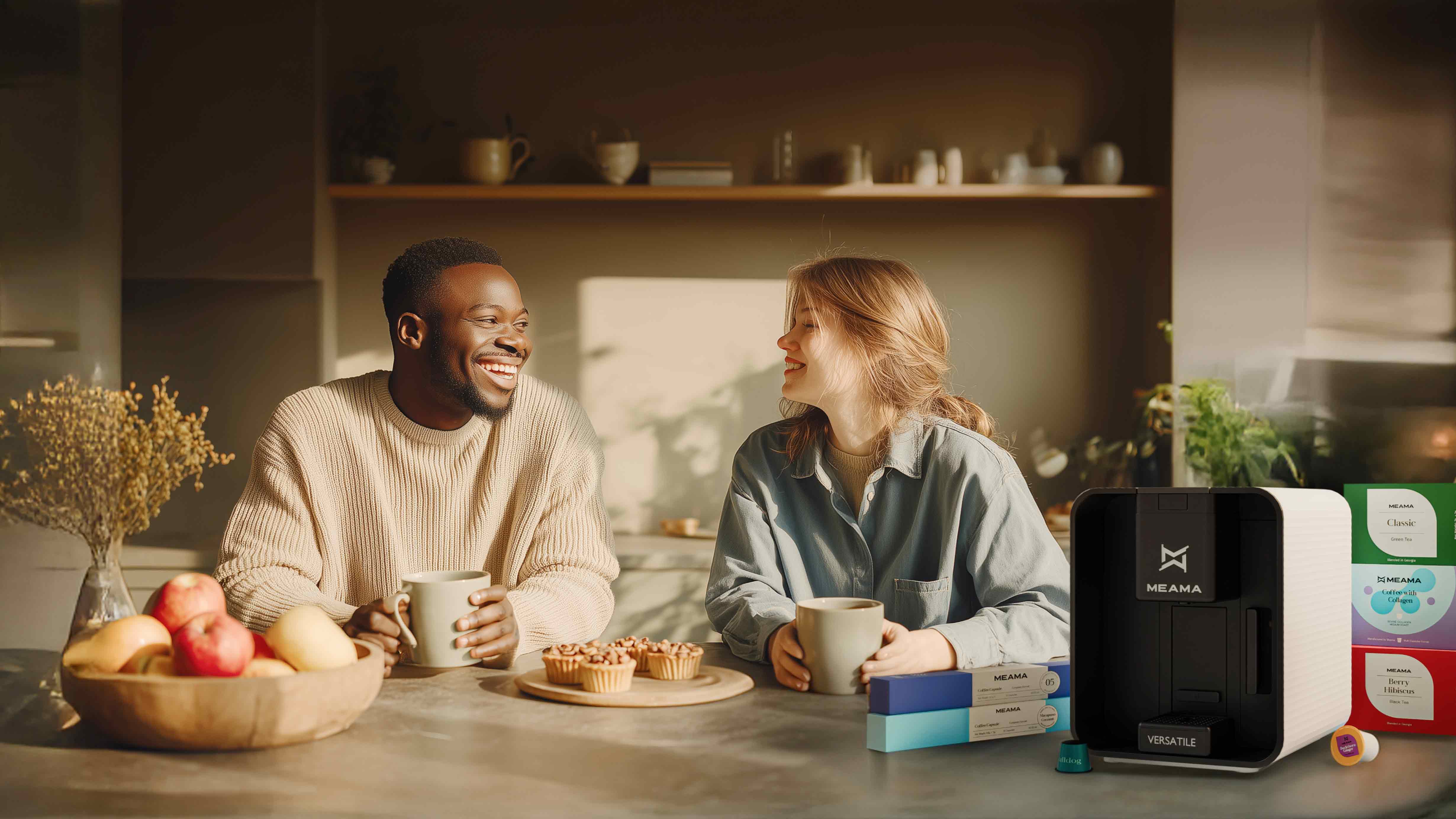 Ein junges Paar sitzt in einer modernen Küche und Trinkt Kaffee vor Ihnen steht die weiße Versatile und 5 Packungen Classic Kapseln, sowohl Espressokapseln als auch Multikapseln. Ein Text im Bild: "Jetzt die Versatile mit Gratis Becher und Gratis Kapselvorrat bestellen"