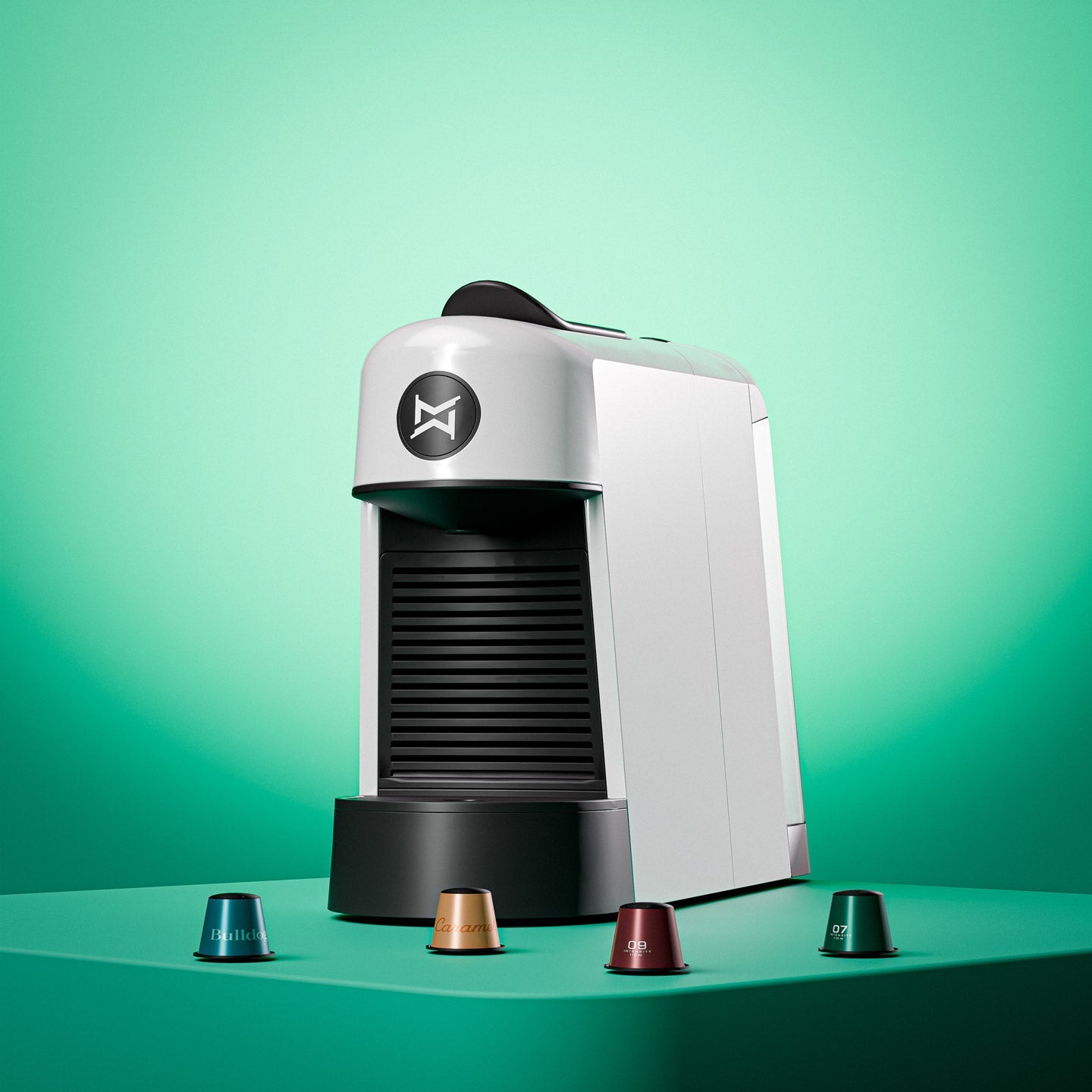 Die weiße Espressomaschine steht auf einem grünen Podest mit einigen Espressokapseln vor sich liegend.