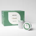 Zwei Multi-Tee-Kapseln der Sorte Classic Green Grüntee stehen im Vordergrund, dahinter die passende Verpackung